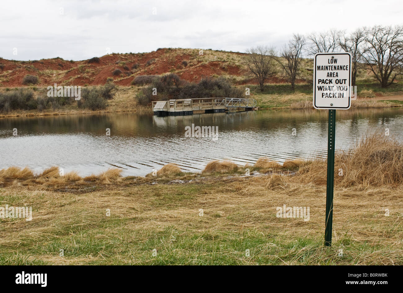 Handicapped access public fishing lake with sign, 'Low maintenance area pack out what you pack in'. Stock Photo