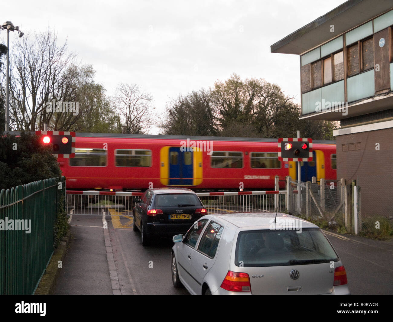 Cars wait at a railway level crossing barrier as train passes through