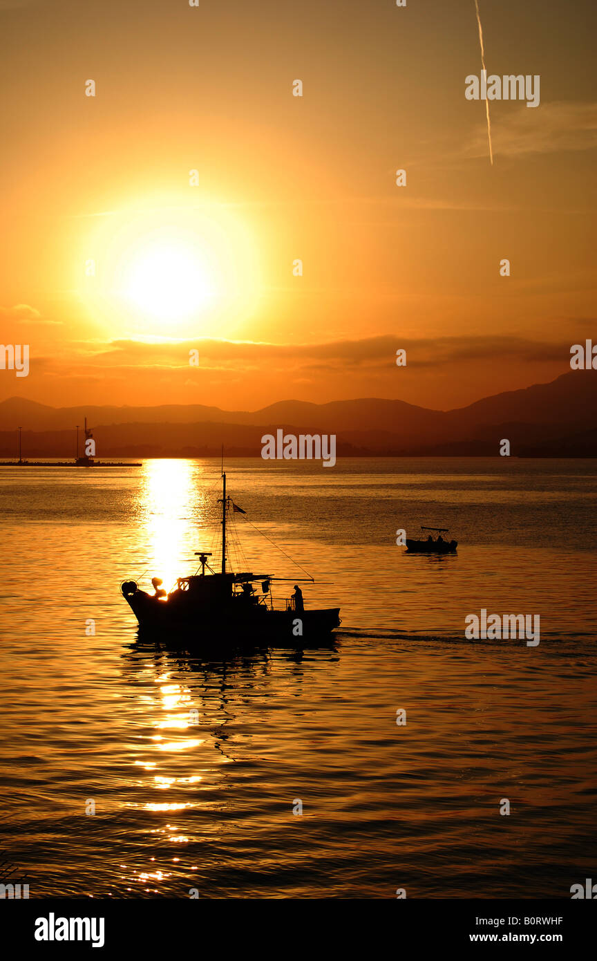 Silhouettes of boats returning to the dock in the sunset Stock Photo ...