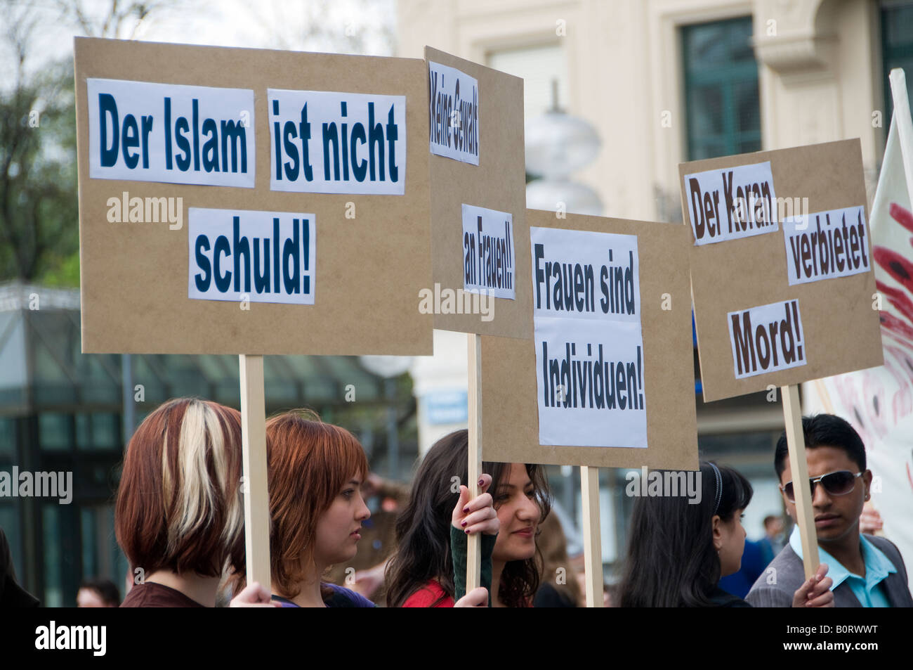 Young Germans hold cardboard signs which reads 'Islam is Not Bad' and 'The Koran Forbids Murder' during a rally against Islamophobia in Munich Germany Stock Photo