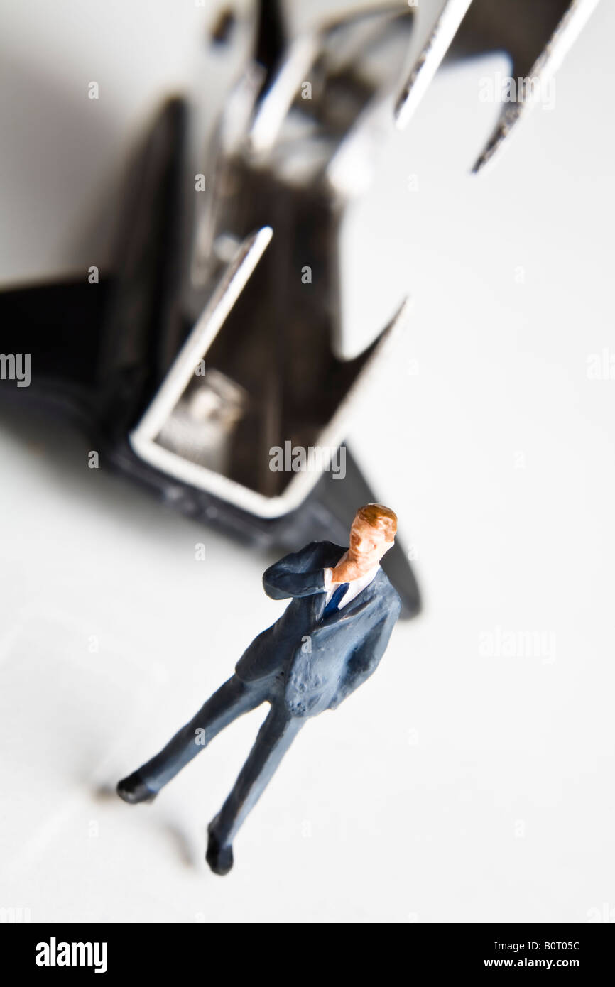 Businessman figurines standing next to a staple remover Stock Photo