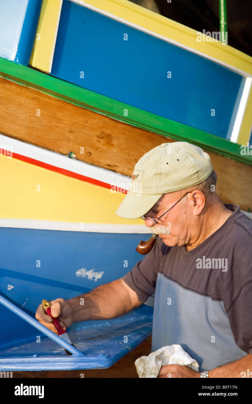 Traditional Maltese fishing boat; Fisherman repainting a Luzzu Eye of Horus or of Osiris on the front to protect the fishermen when they are at sea. Stock Photo