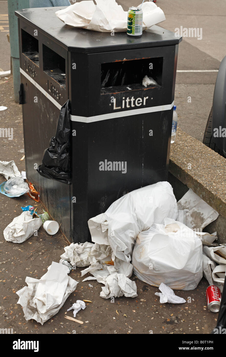 Piles of litter beside a litter bin in the street. Stock Photo