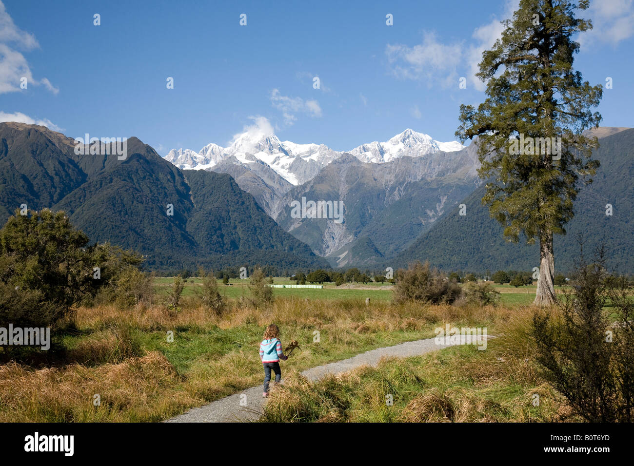 view from lake matheson south island new zealand towards mount cook and mount tasman including rear view of a young girl Stock Photo