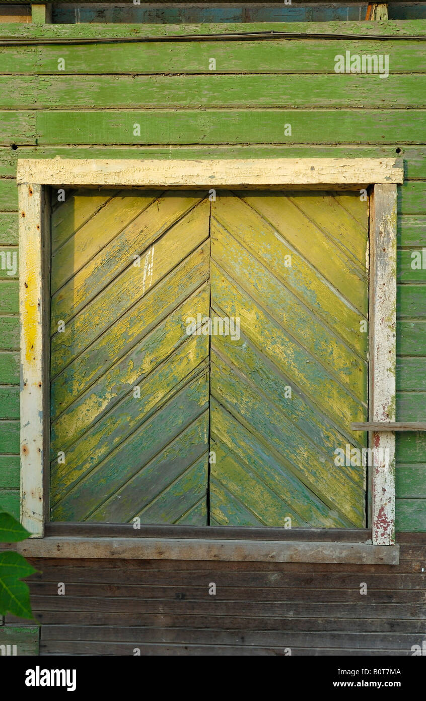 colored old boards of a window shutter green and yellow color are splintering off background Stock Photo