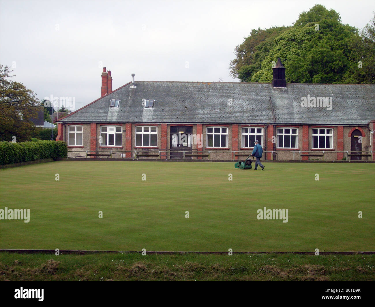 English bowling green pavilion, Scalby Village Scarborough, England. Being mowed by groundsman. Stock Photo