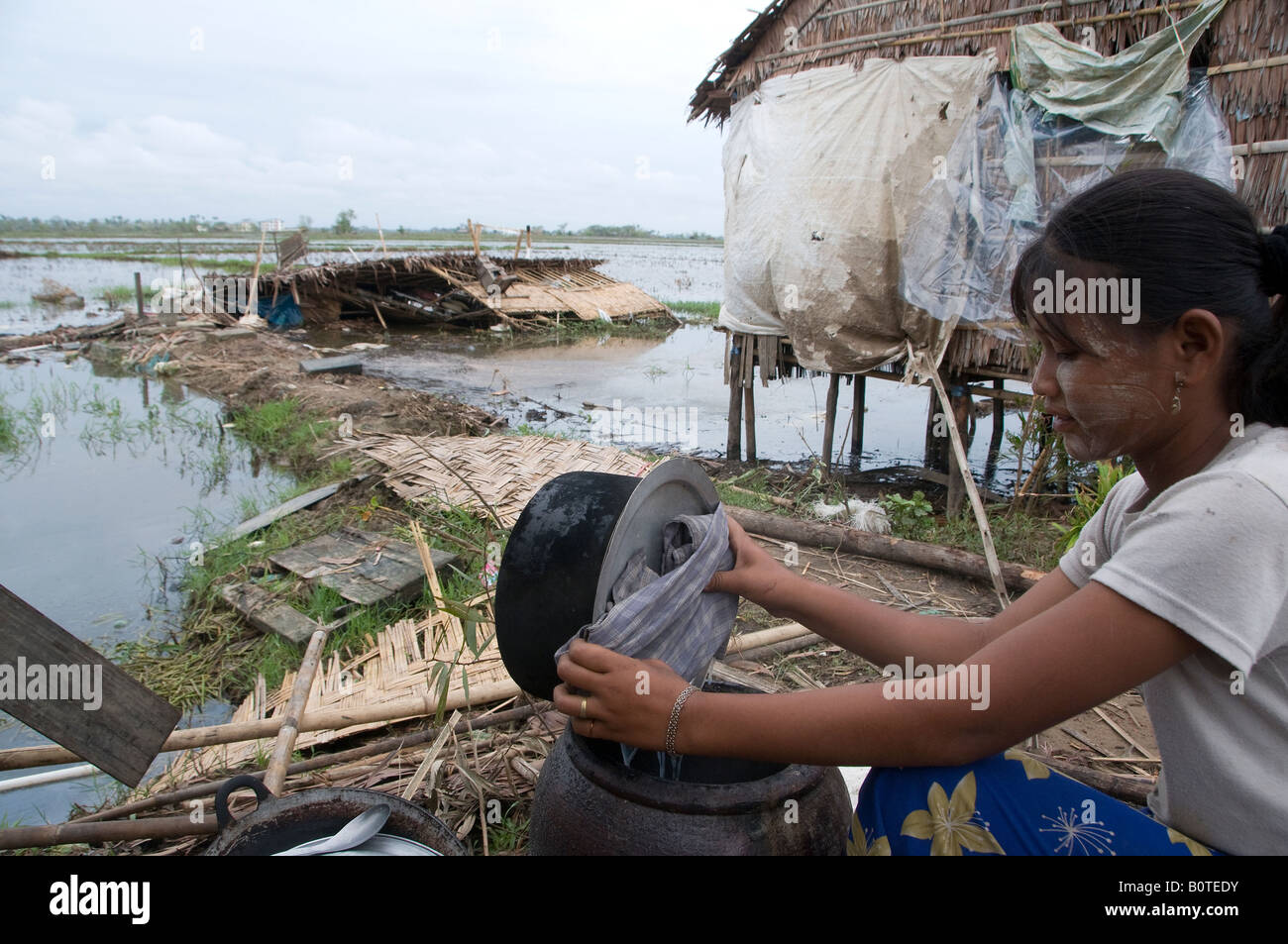 A villager cooks next to her home downed by Cyclone Nargis in a flooded rural area near Yangon Myanmar Stock Photo