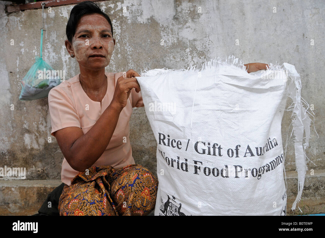 Woman holds a sack with writing reading ' Rice / Gift of Australia World Food Program' during food distribution carried out by WFP in Myanmar Stock Photo