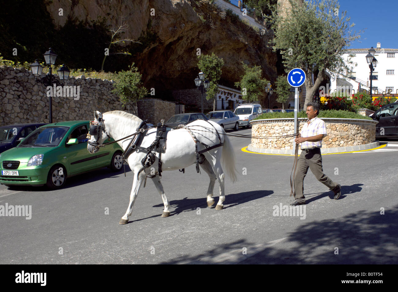 Man walking a white horse on reigns through the streets of Mijas Pueblo, Costa del Sol, Andalucia, Spain Stock Photo