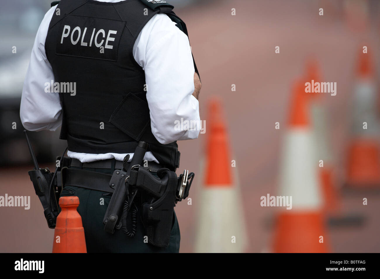 PSNI police service northern ireland officer sergeant standing watching traffic in coned off roadside area ni Stock Photo