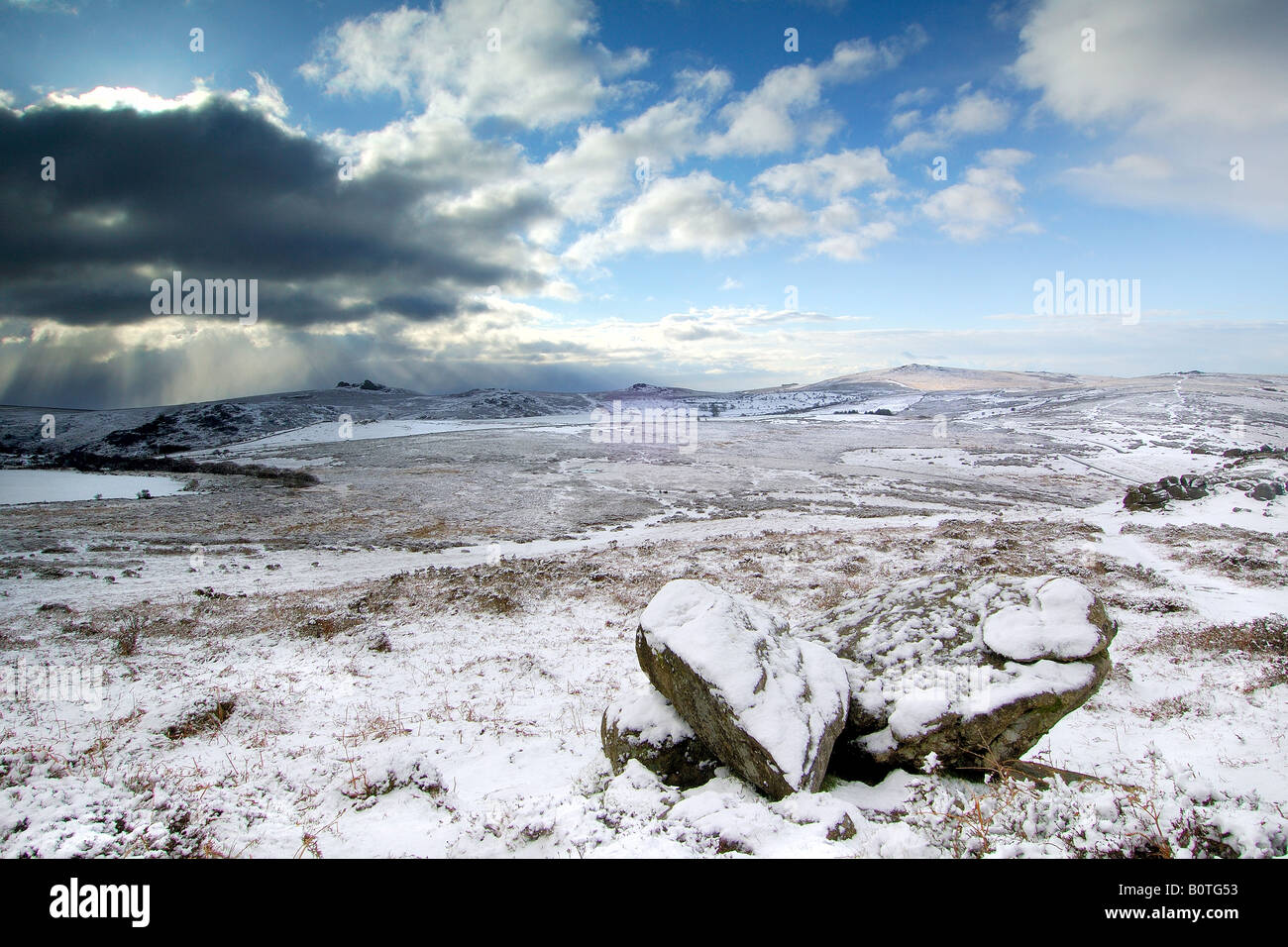 Heavy snow near Chinkwell Tor on Dartmoor National Park with two granite boulders in the foreground and a stormy sky Stock Photo