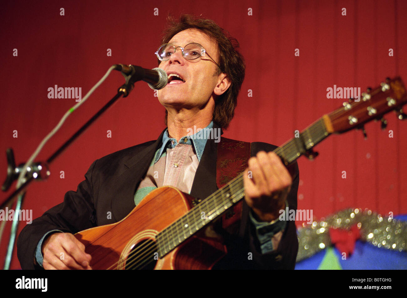 Cliff Richard performing singing and playing guitar in 1993 Stock Photo