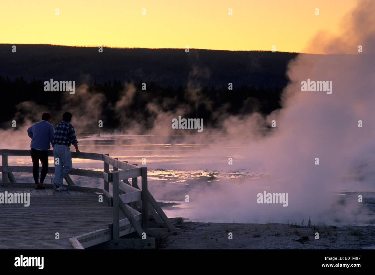 Tourists watching Fountain Geyser at sunset Fountain Paint Pot area Yellowstone National Park Wyoming Stock Photo