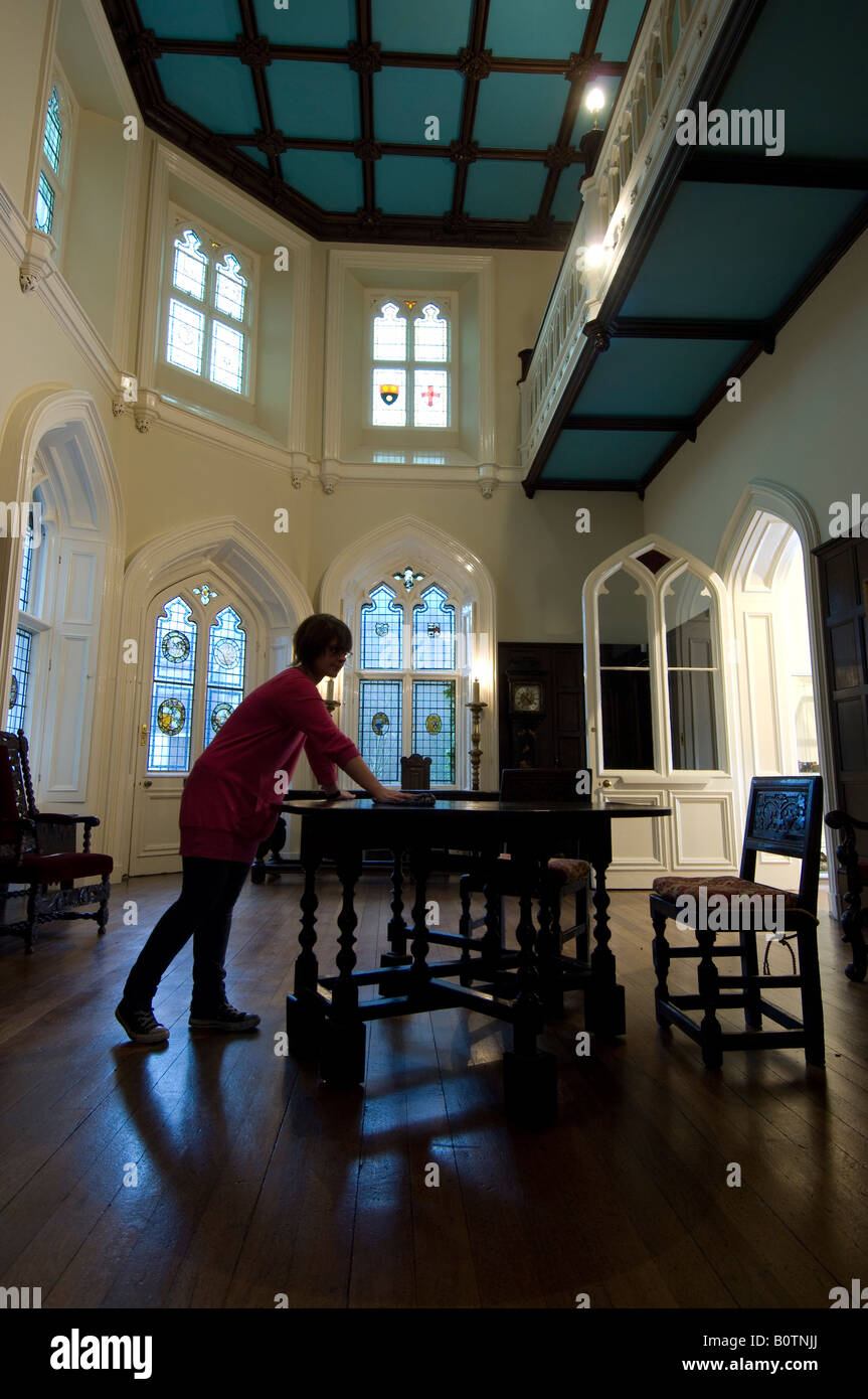 A woman dusts furniture in the Great Hall of Chiddingstone Castle near Tunbridge Wells Kent as it is opened to the public. Stock Photo