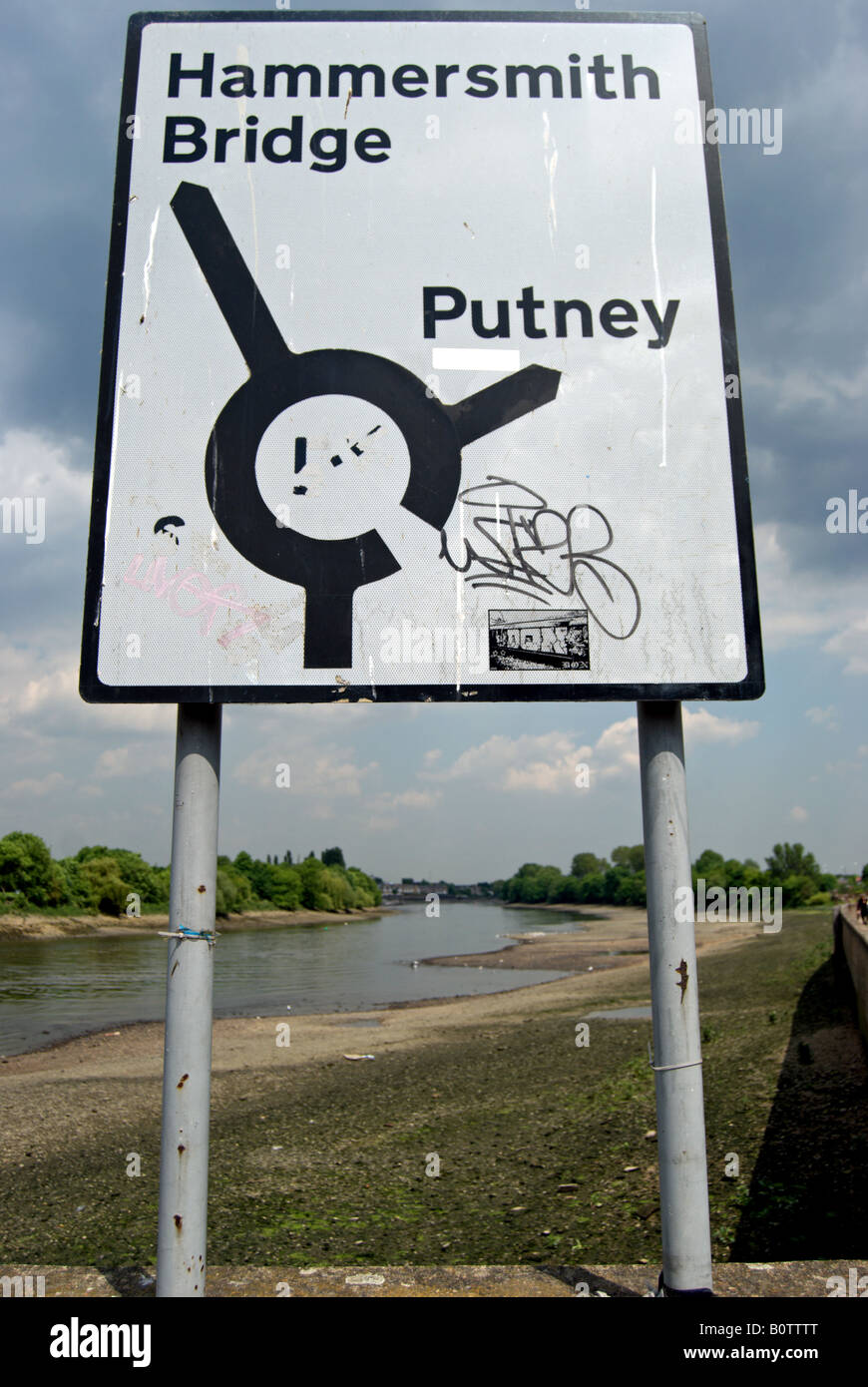 british black and white road sign daubed with graffiti, in barnes beside the river thames at low tide, southwest london, england Stock Photo