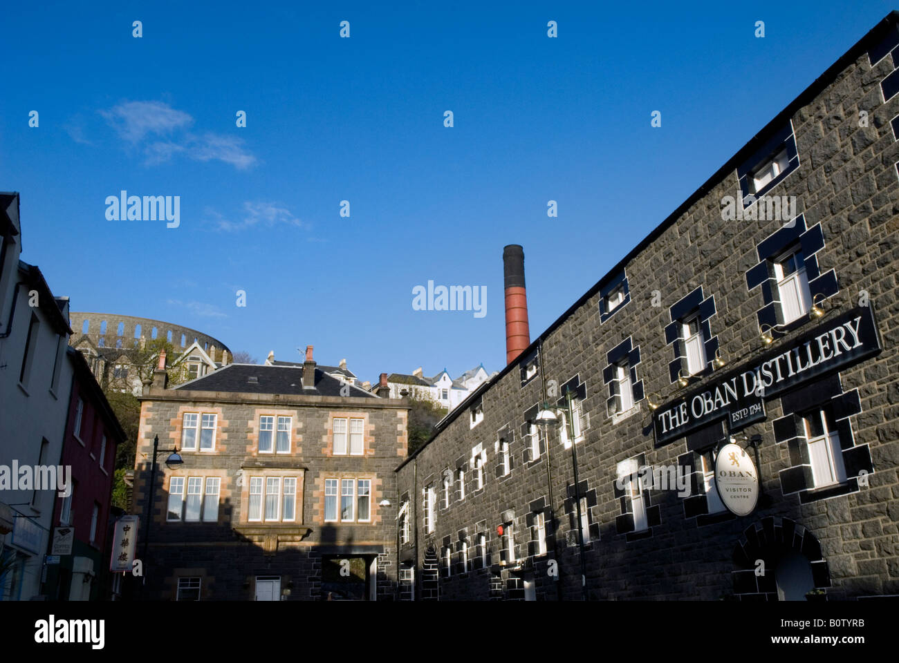 Oban distillery with McCaig's Tower in background, Oban, Scotland Stock Photo