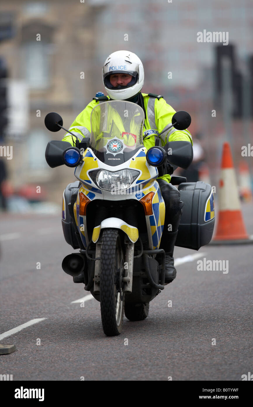 PSNI police service northern ireland motorcycle officer on patrol wearing helmet driving through city centre Stock Photo