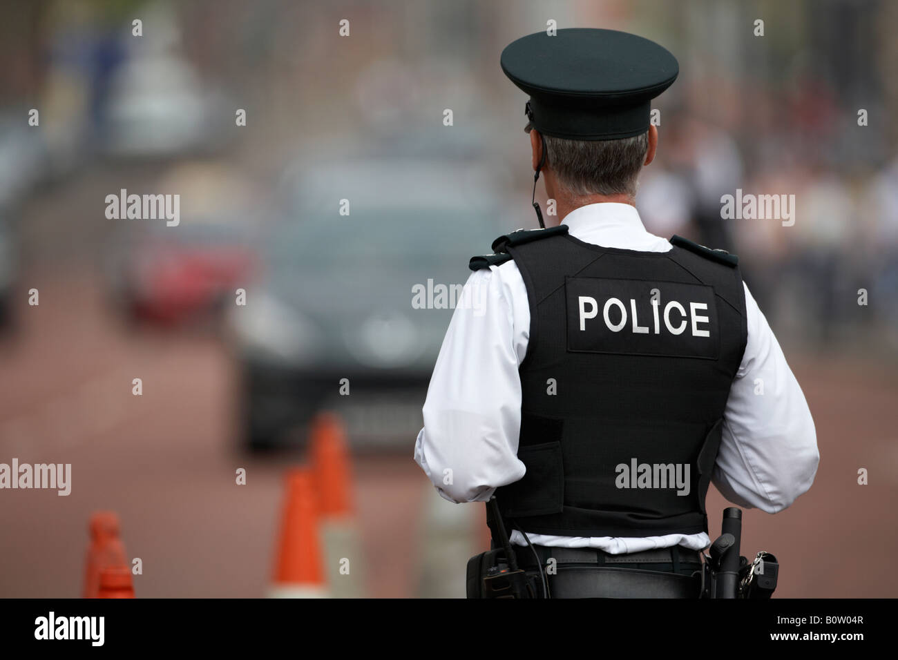 PSNI police service northern ireland officer sergeant standing watching traffic in coned off roadside area Stock Photo