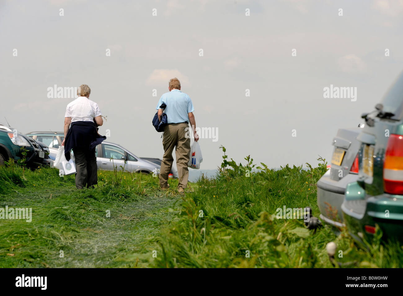 Country show: a couple return to their car parked in a field. Picture by Jim Holden. Stock Photo