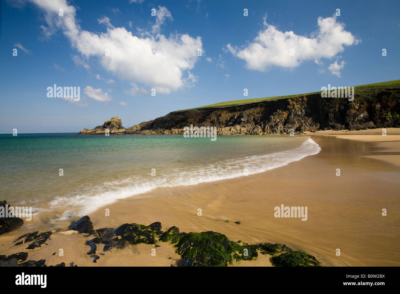 Cornish Beach and cliffs with blue sky clouds and rocks, early morning, sea going out, low tide, freshly washed sand, landscape Stock Photo