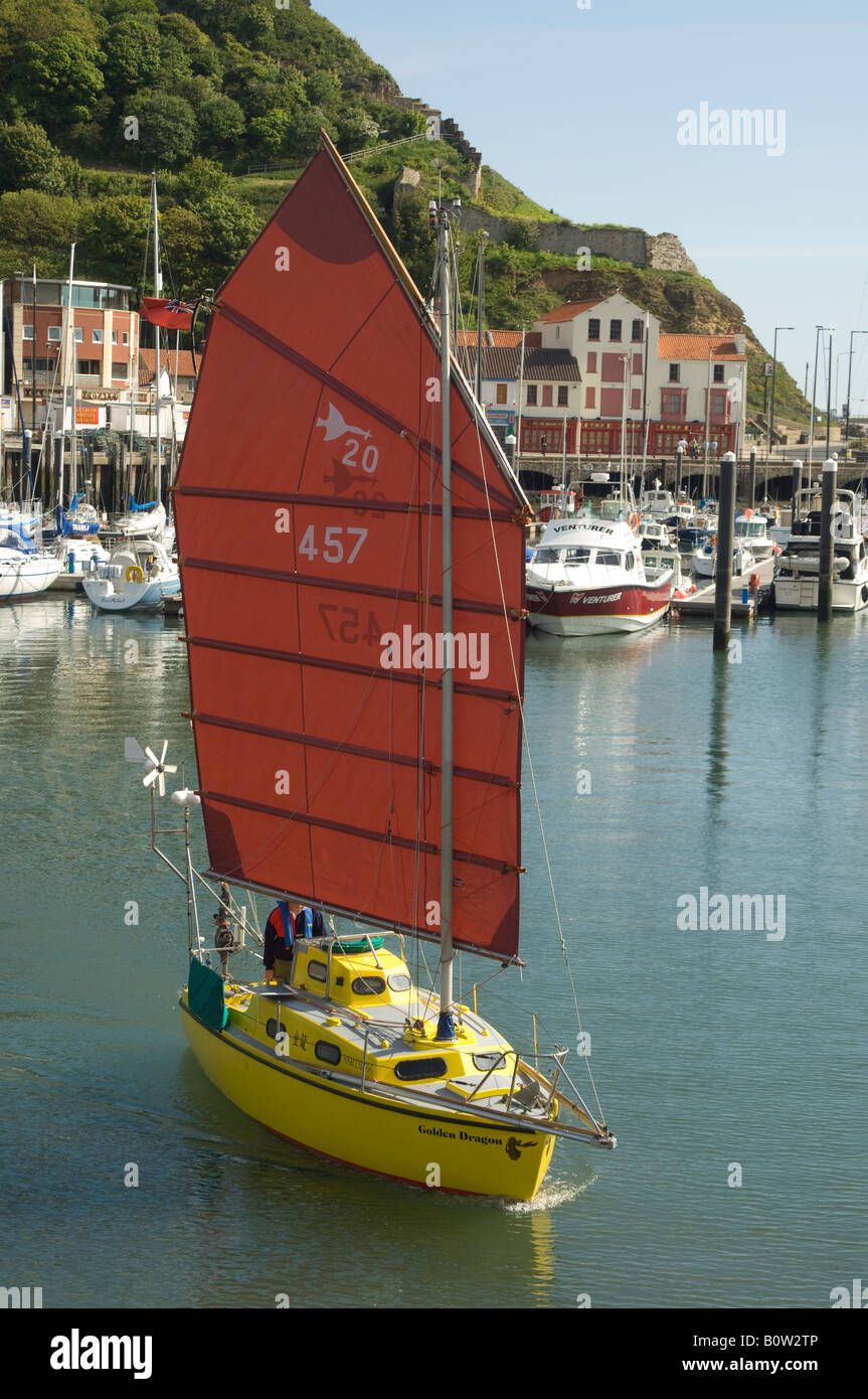 Junk rigged yacht departing from Scarborough harbour, North Yorkshire, UK Stock Photo