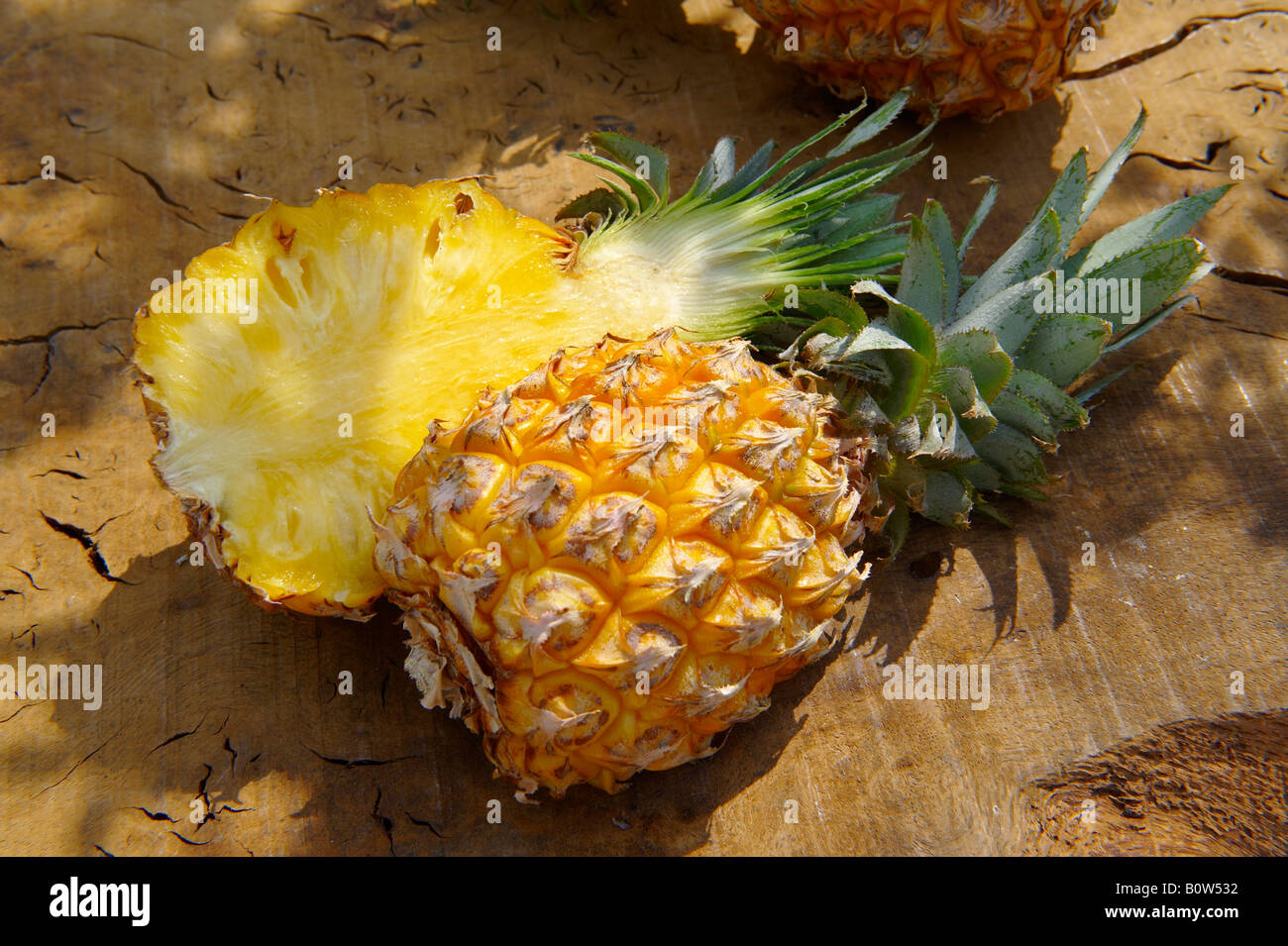 Fresh Victoria Pineapple cut in half  on a wooden garden table in the sun Stock Photo