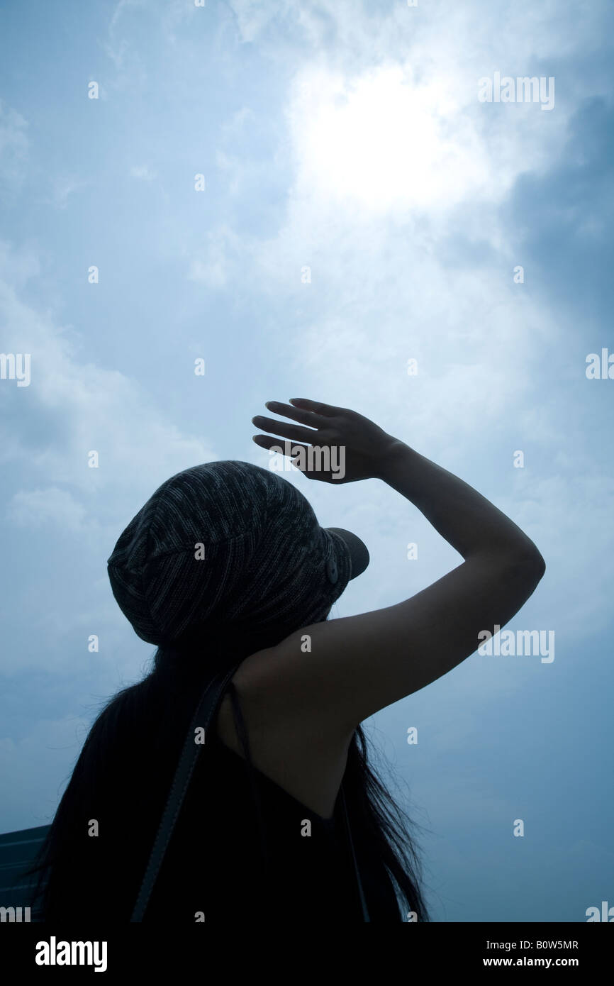 Woman shielding eyes from the sun Stock Photo