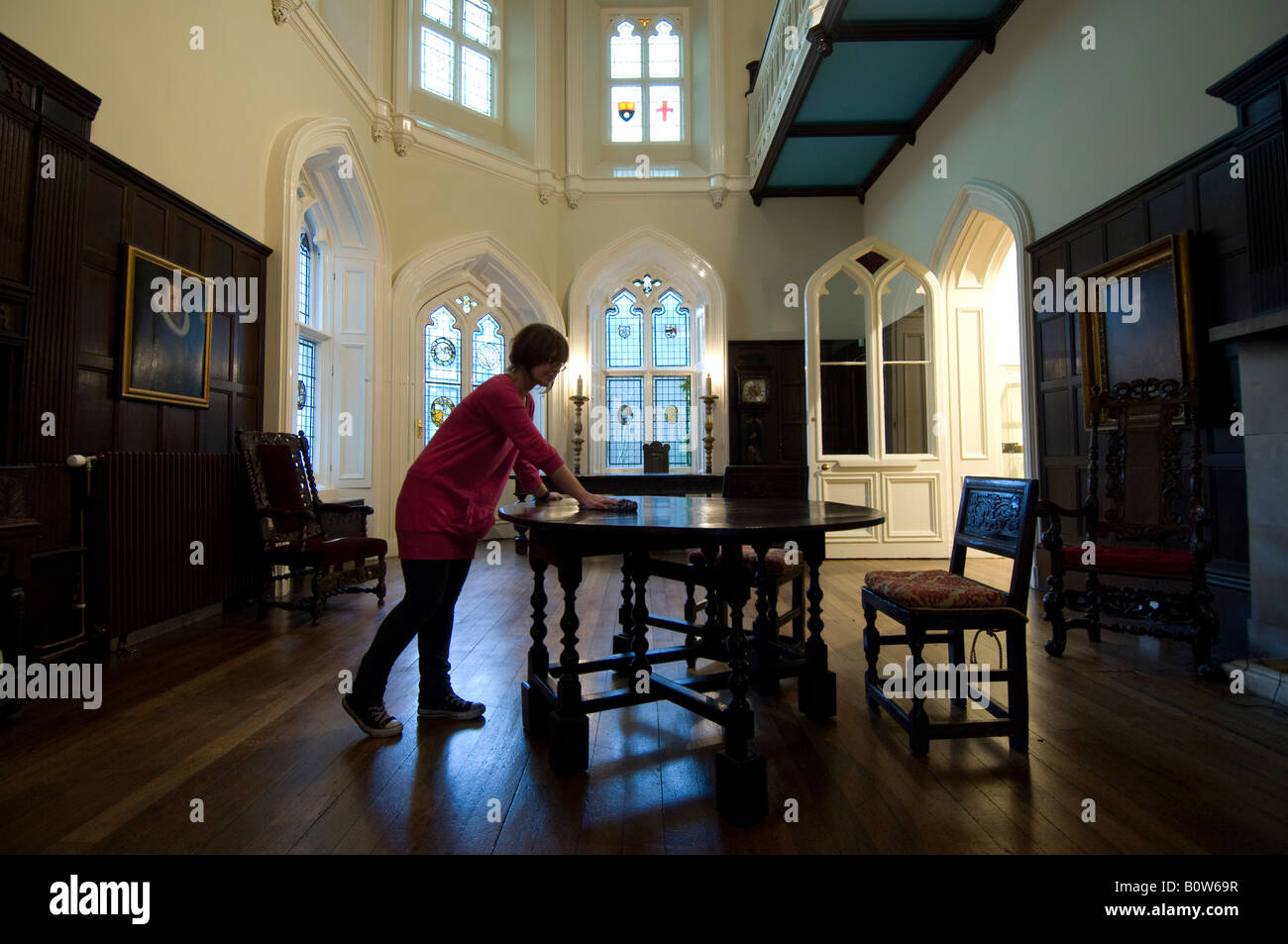 A woman dusts furniture in the Great Hall of Chiddingstone Castle near Tunbridge Wells Kent as it is opened to the public. Stock Photo