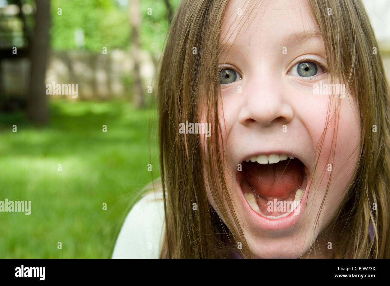 Closeup of little girl's face, mouth wide open as she yells. Stock Photo