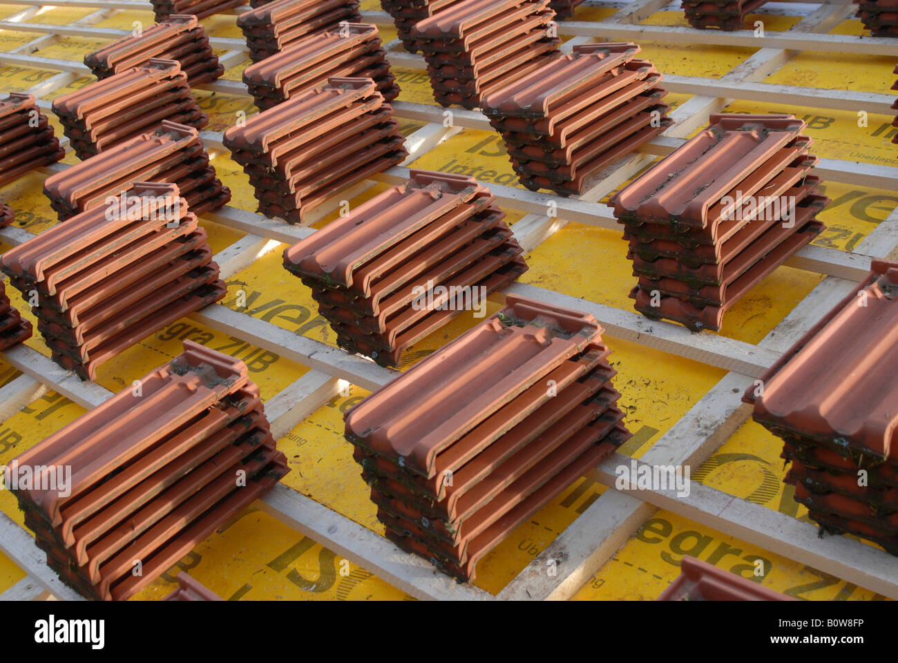 Roofing tiles resting on wooden roof slats at a construction site ready for laying Stock Photo