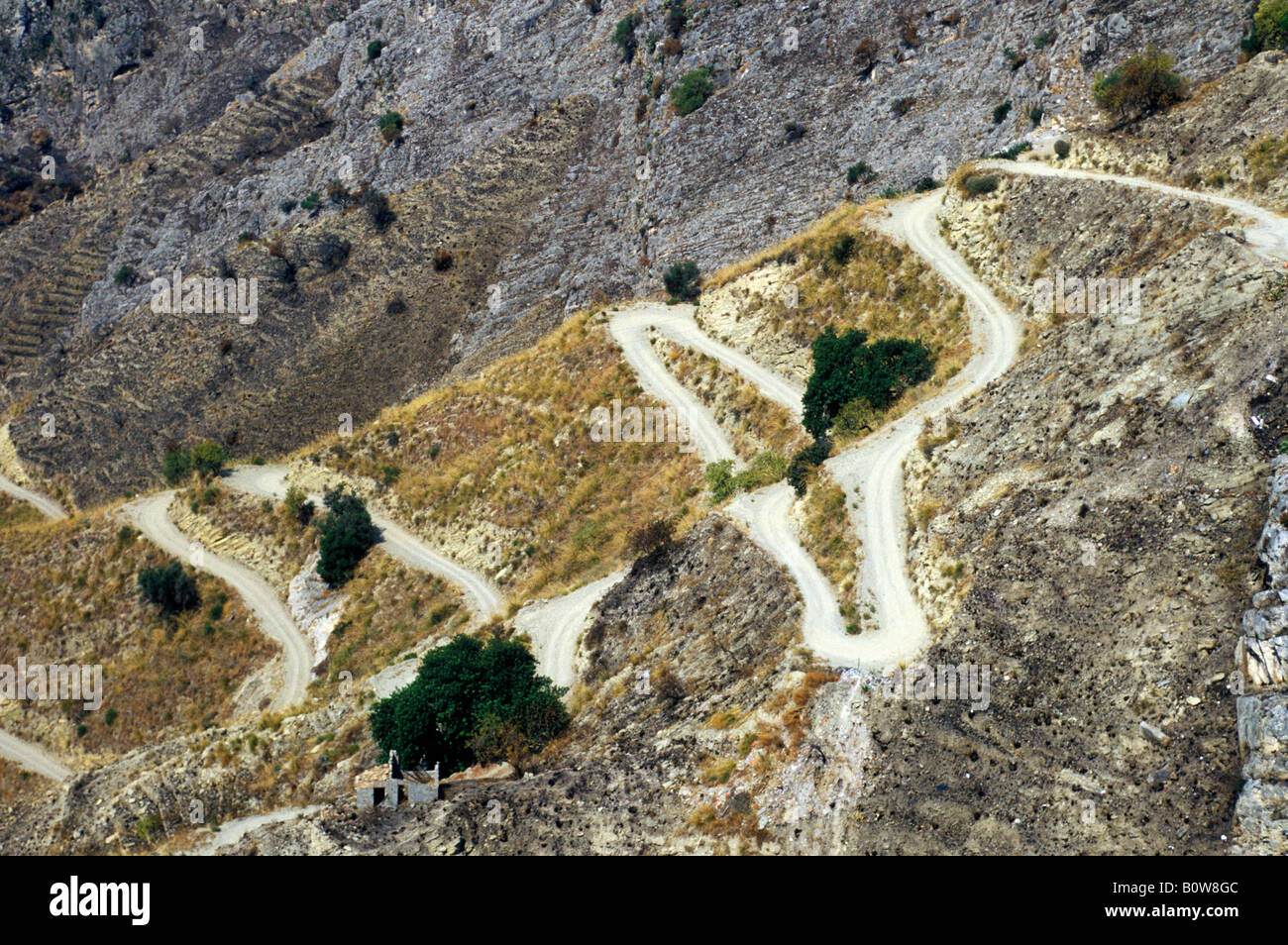 Road winding up arid landscape with sparse vegetation, Castelmola near Taormina, Sicily, Italy, Europe Stock Photo