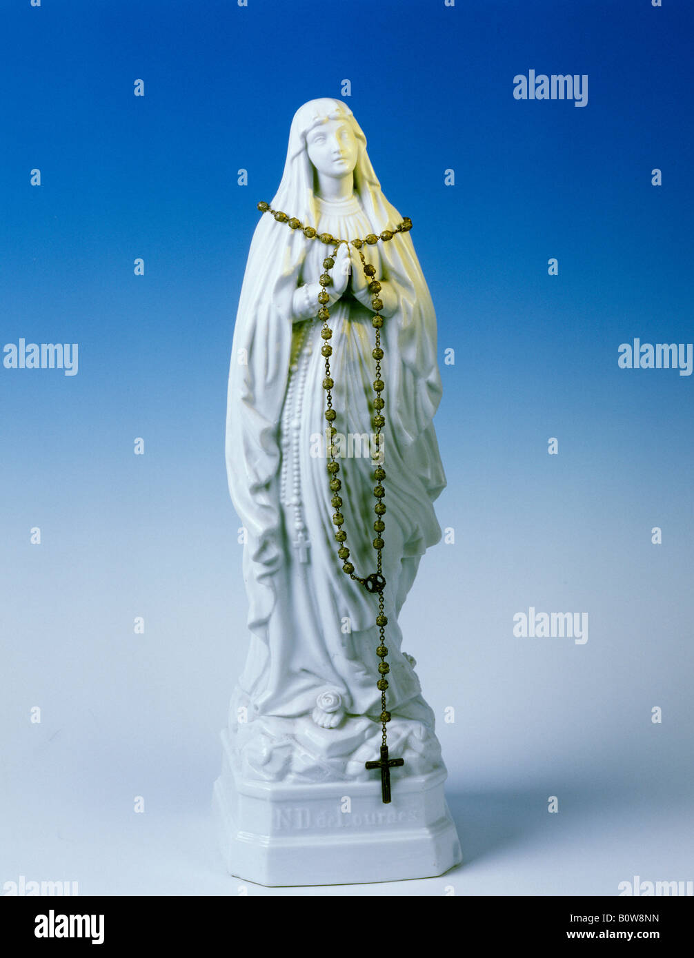 Rosary beads draped over a statue of Our Lady of Lourdes Stock Photo