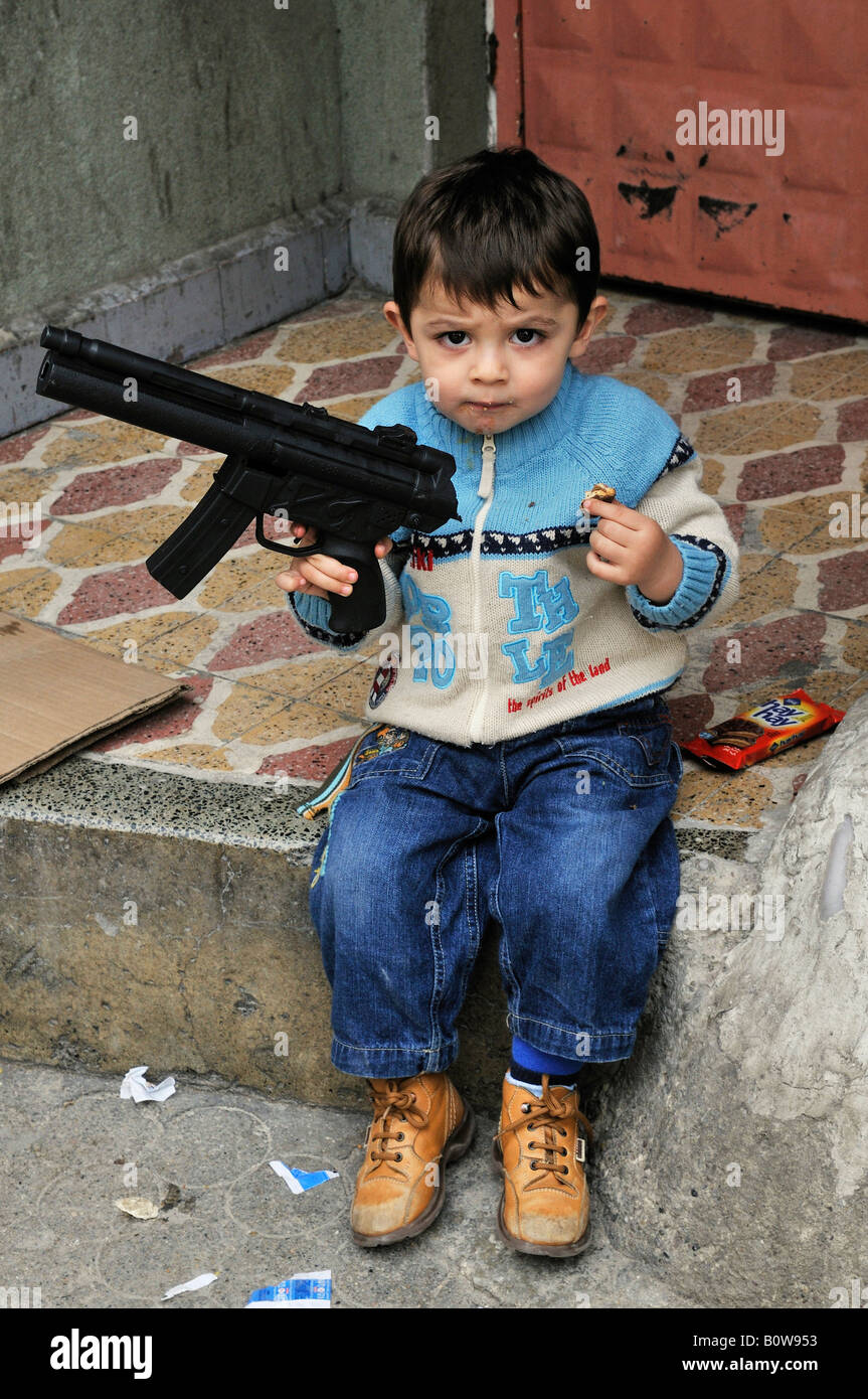 Boy brandishing a toy plastic machine gun, Istanbul, Turkey Stock Photo