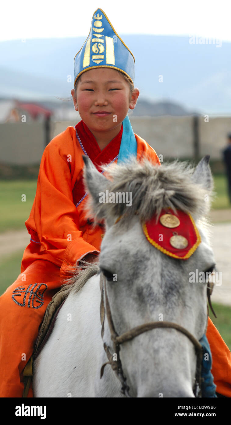 Ten-year-old girl wearing hat with soyombo emblem riding a horse as a participant in the horsemanship competitions of the Naada Stock Photo