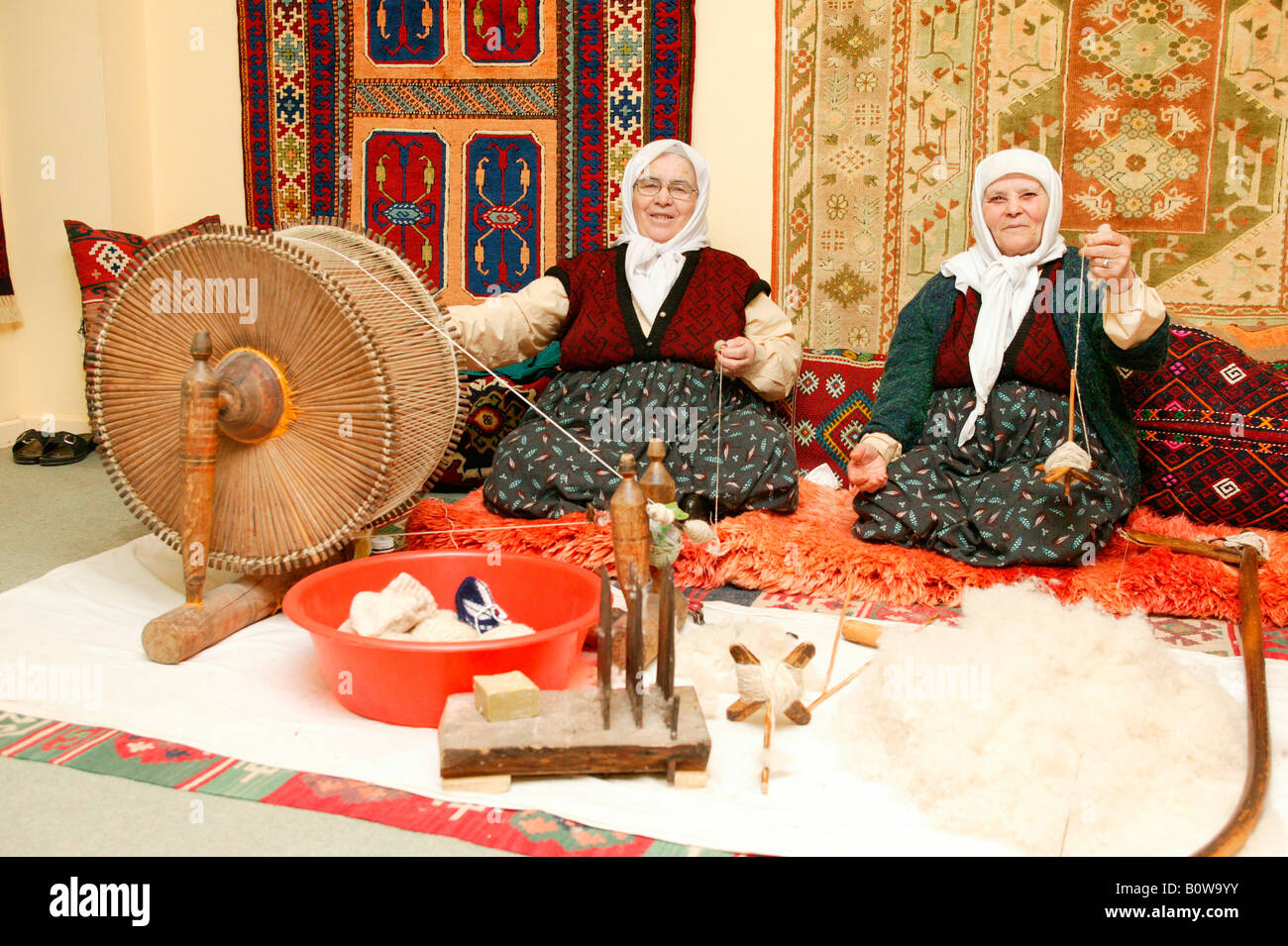 Two old women making yarn with spinningwheel and spindle, carpet