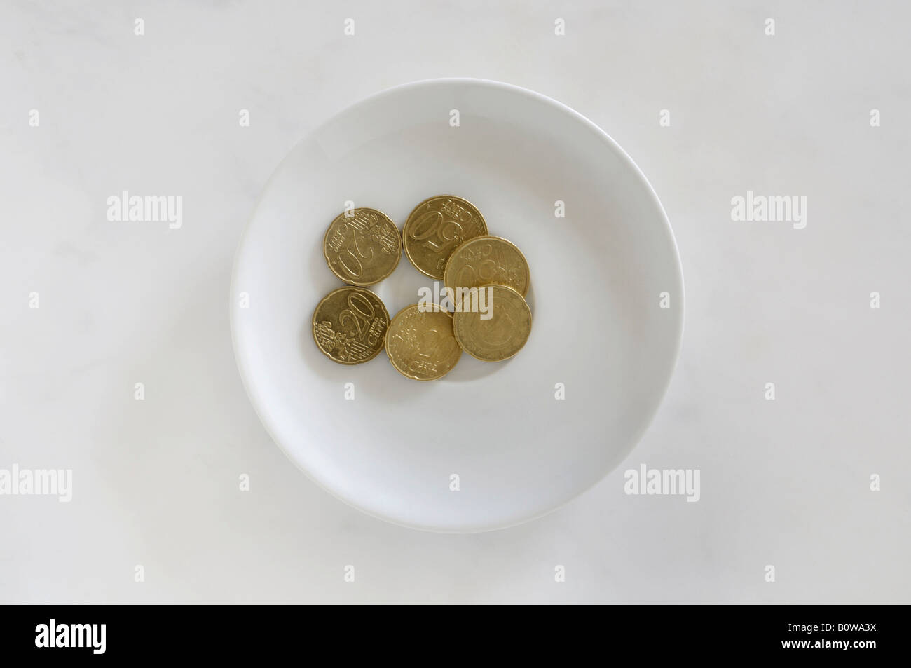 Euro coins on a white plate on a marble surface, payment for toilet use Stock Photo