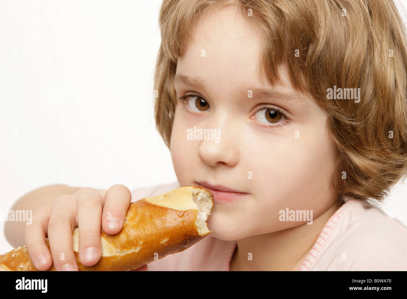 8-year-old girl eating a baguette Stock Photo