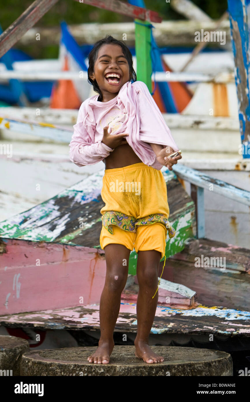 Young laughing girl standing in front of fishing boats, Lombok Island, Lesser Sunda Islands, Indonesia Stock Photo