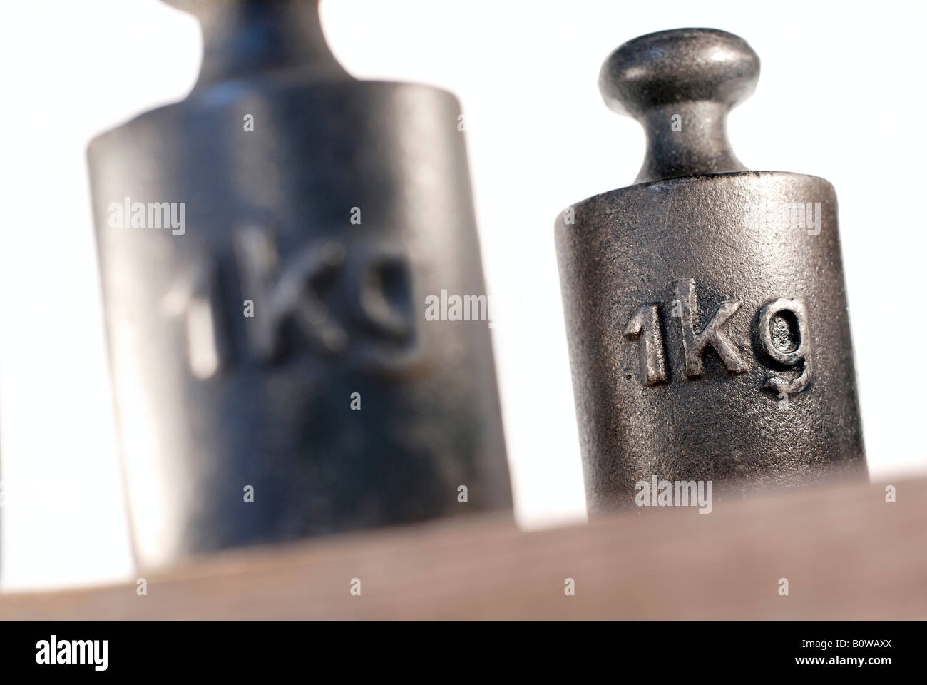 Two 1 kg, kilogramme weights on wooden surface Stock Photo