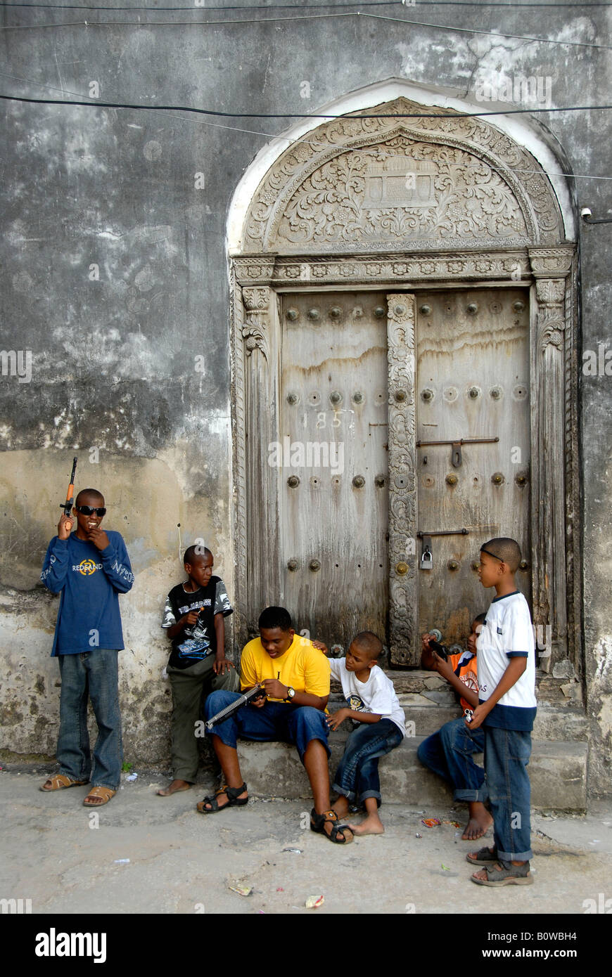 Street scene, kids standing in front of an old door in Stone Town, Zanzibar, Tanzania, Africa Stock Photo