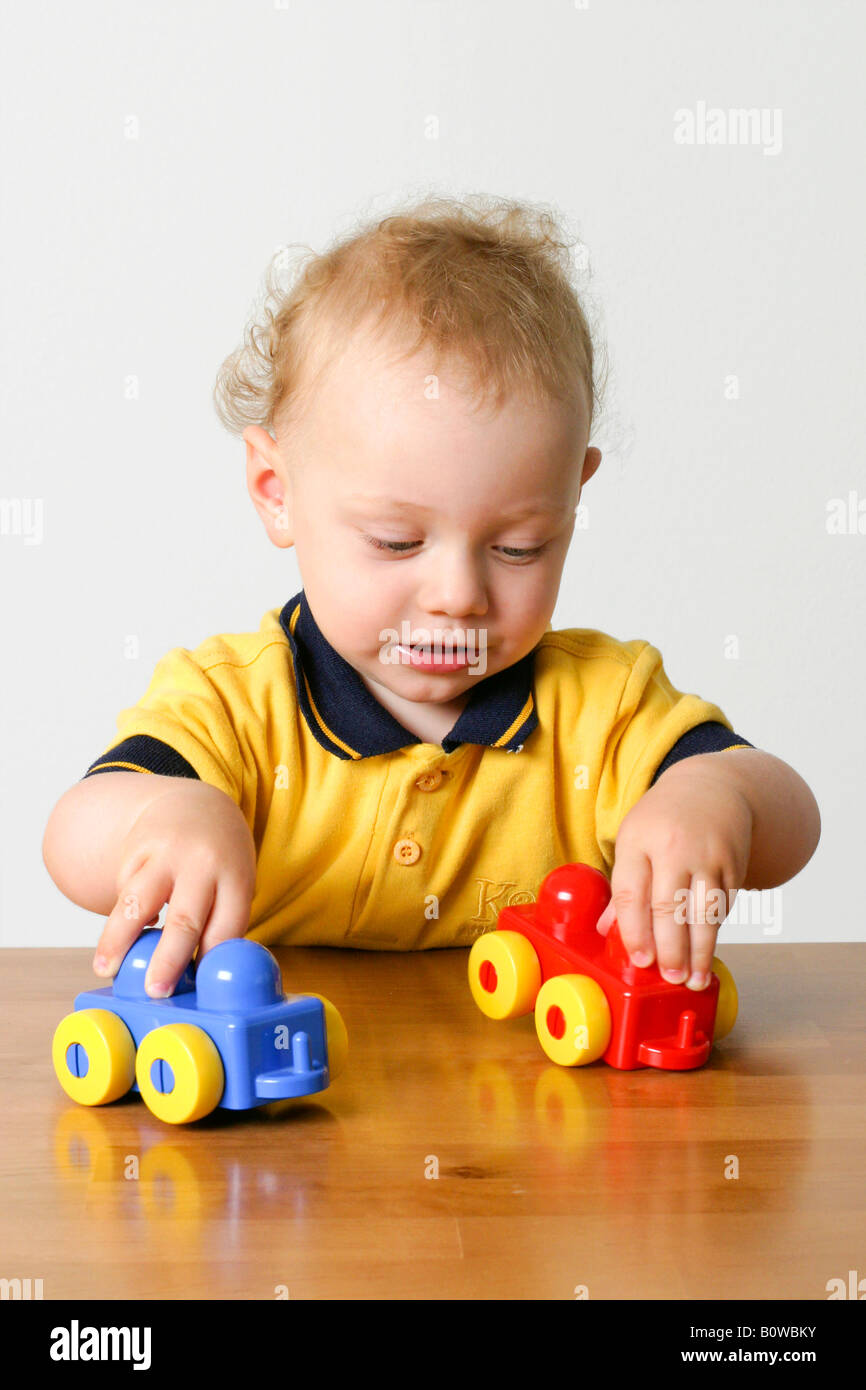 One-year-old boy playing with two toy cars Stock Photo