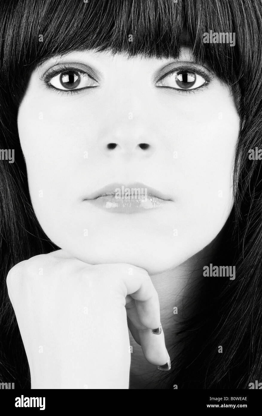 Portrait of a girl with black hair and big eyes resting her chin on her hand, black and white Stock Photo