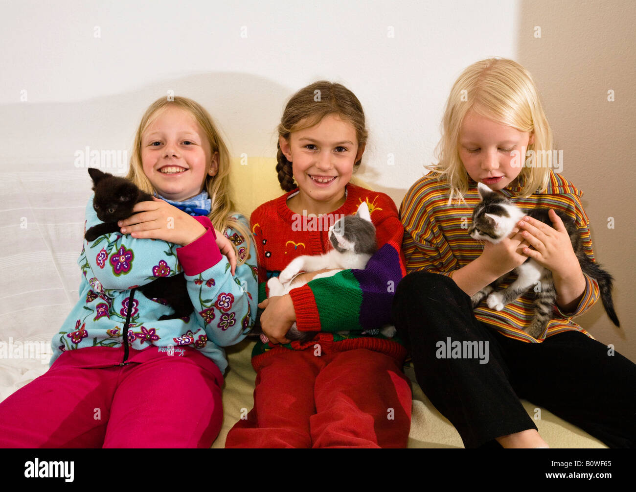 Three girls holding kittens in their arms Stock Photo