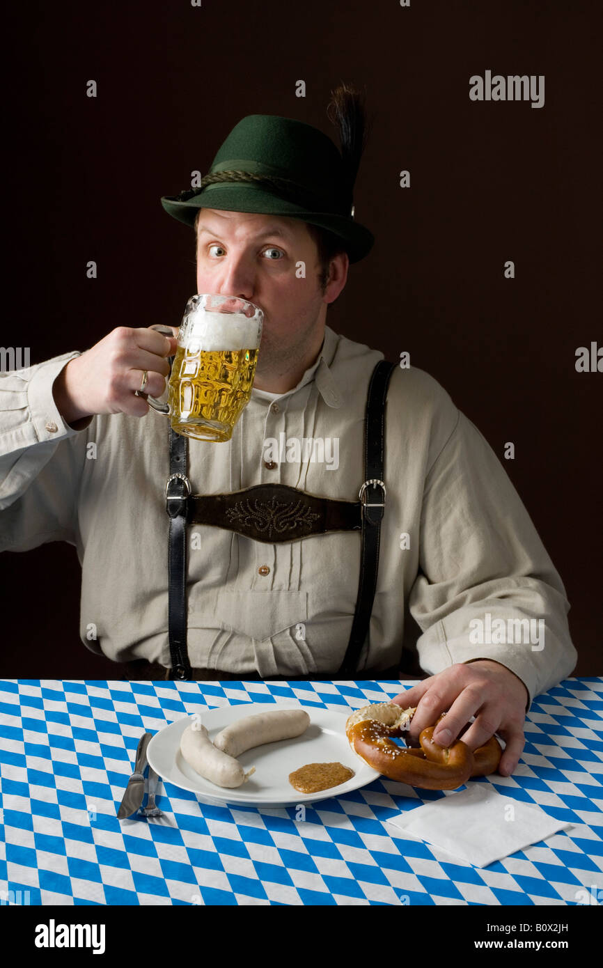 Stereotypical German man in Bavarian costume drinking a beer and Stock