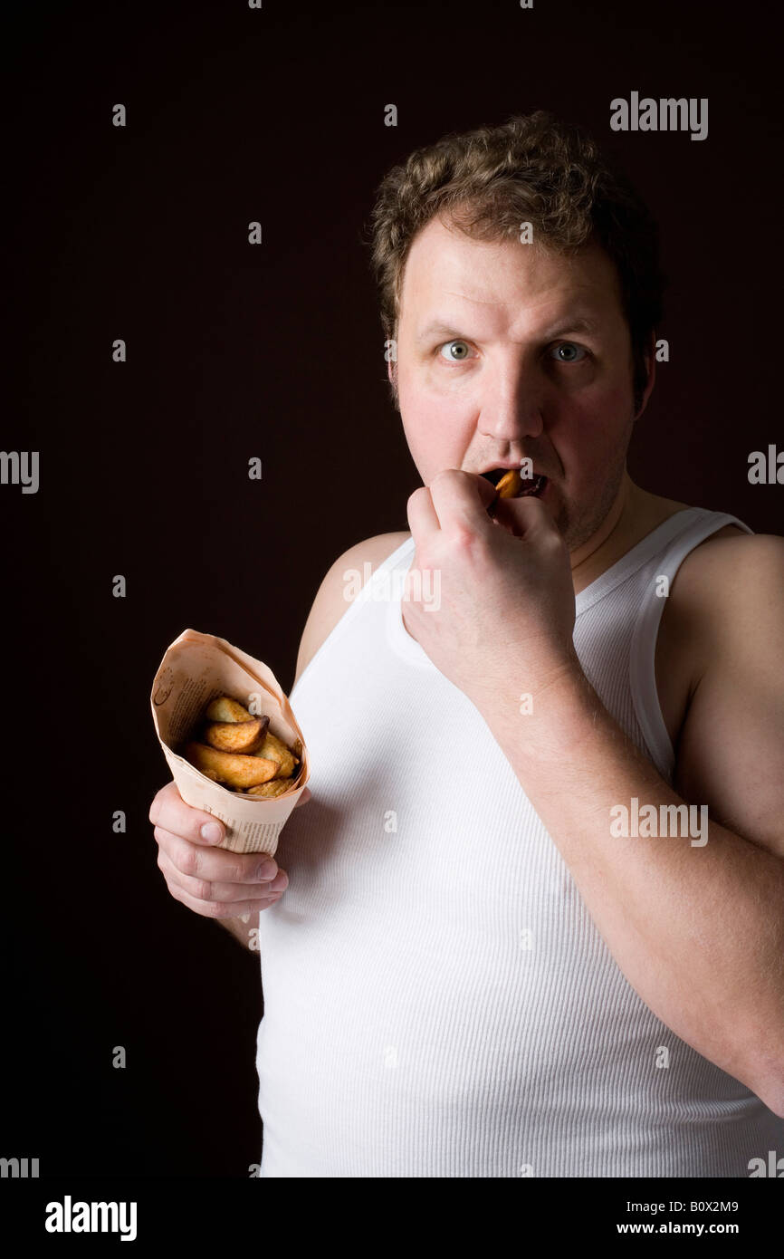 Stereotypical Englishman eating fish and chips in wrapped newspaper Stock Photo