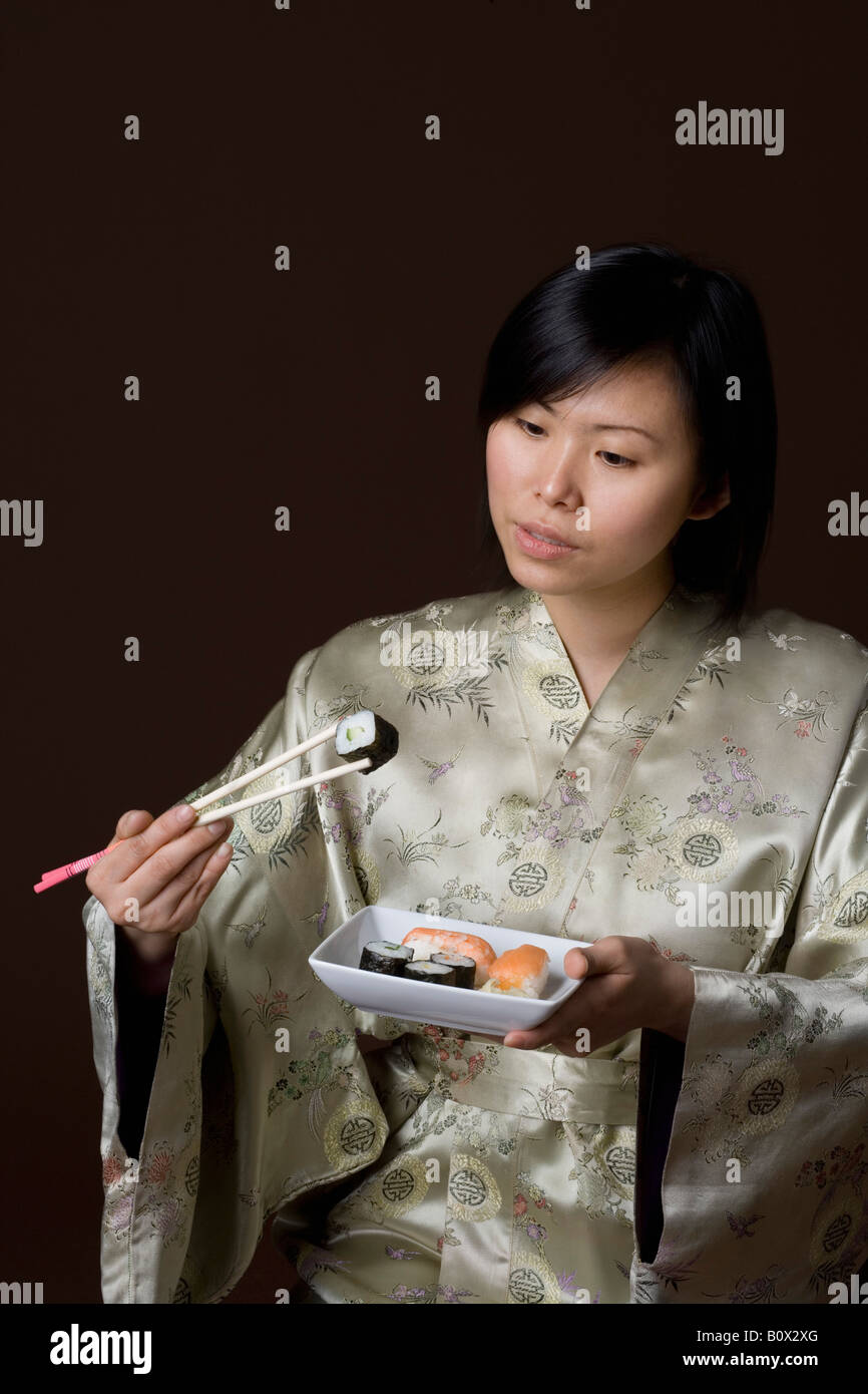 A woman dressed in a kimono eating sushi Stock Photo