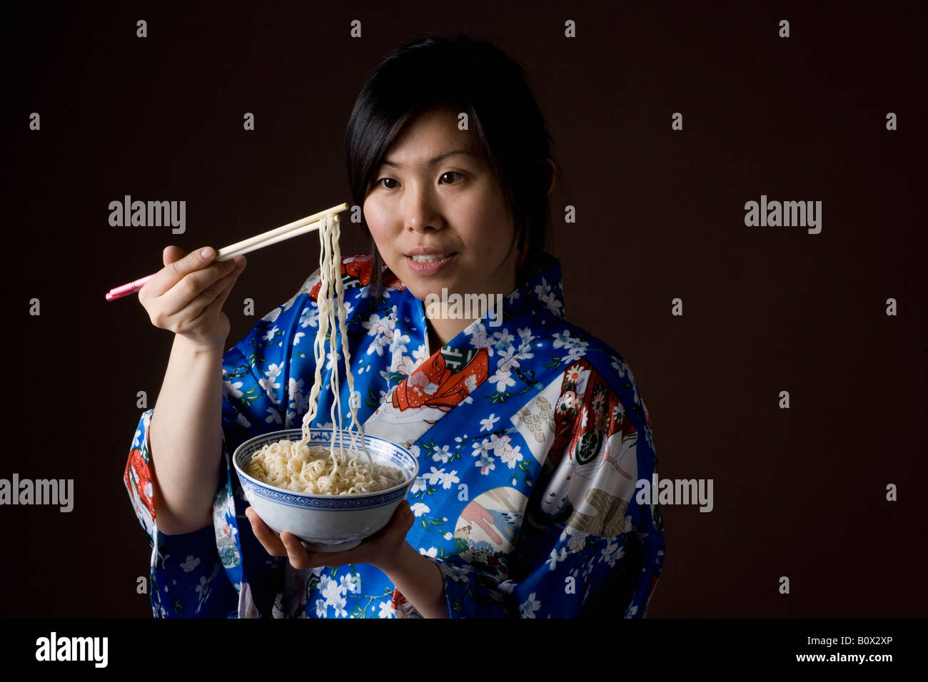 A woman dressed in a kimono eating noodles Stock Photo