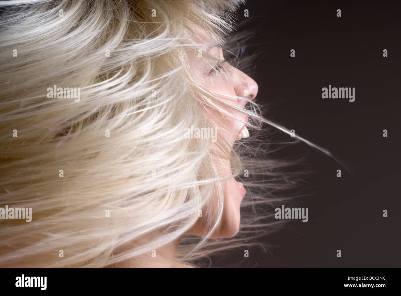 A woman tossing her hair with her mouth open Stock Photo