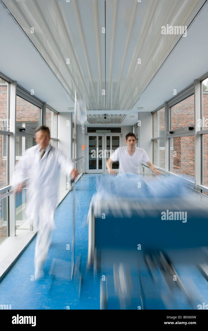 Two healthcare workers pushing a hospital bed along a corridor Stock Photo