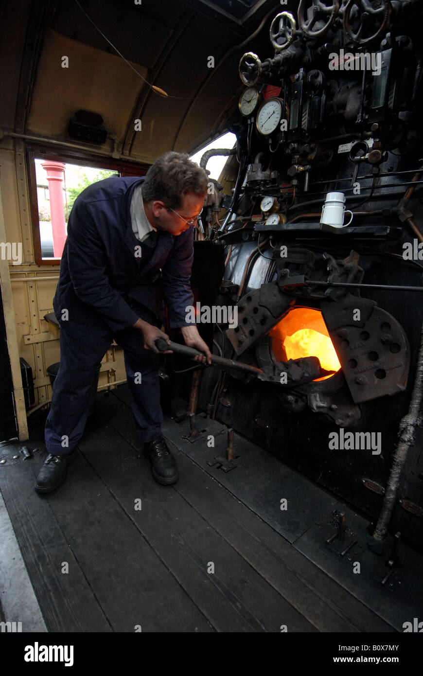 A fireman on the footplate shoveling coal on the steam of